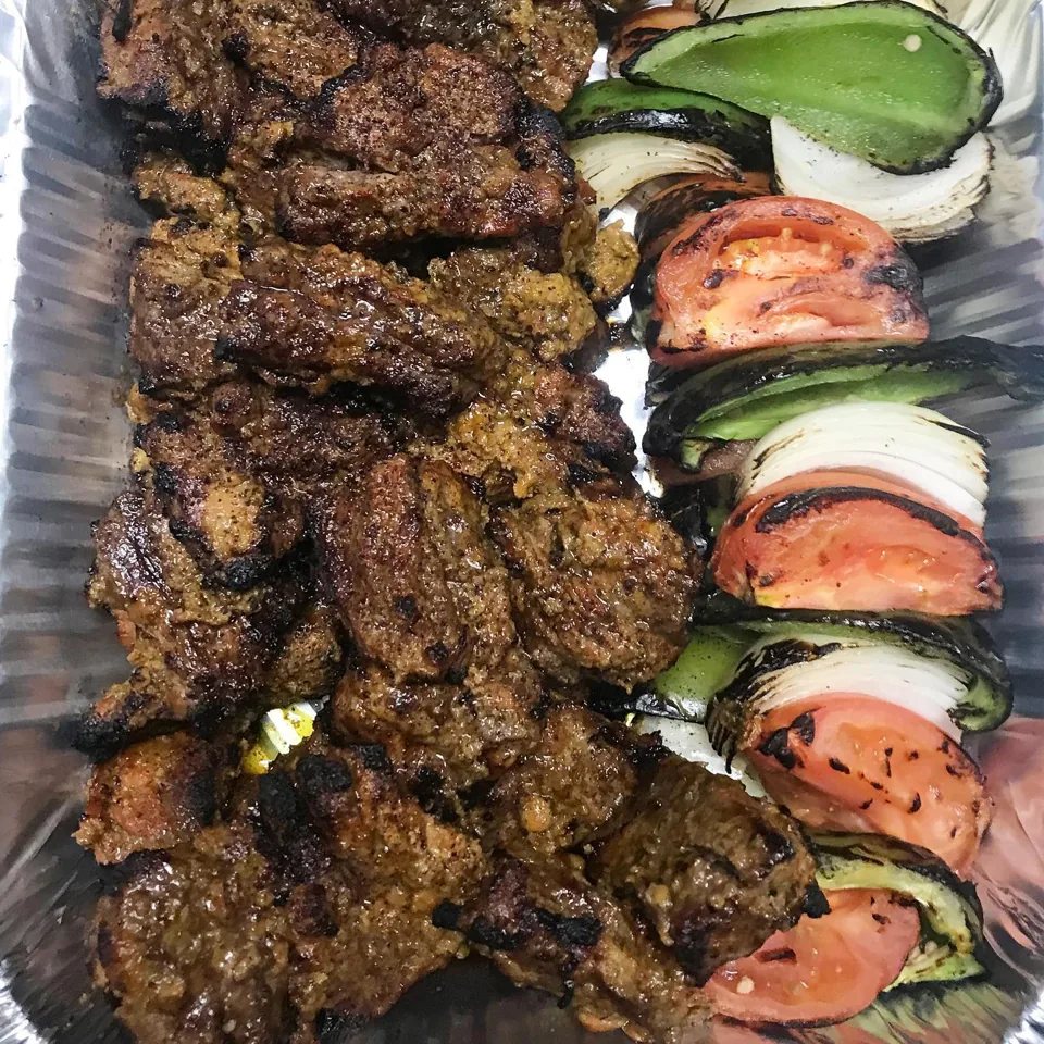 Beef chenjeh and charbroiled vegetables in a catering tray